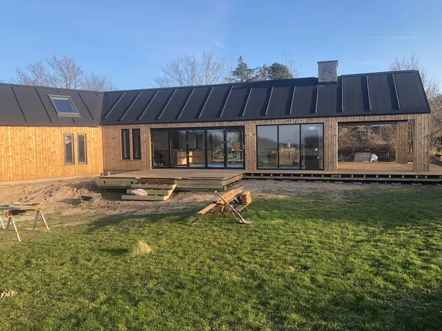 Langstrakt sommerhus i træ set fra haven — billede 3 af 21