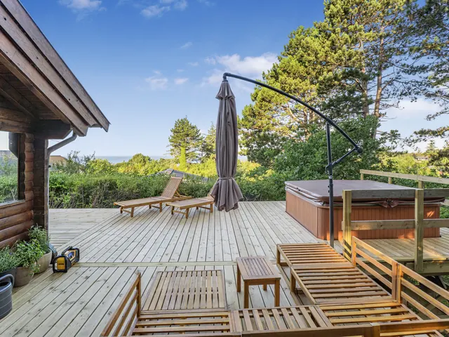 Terrassen set fra bjælkehuset med spabad og parasol — billede 23 af 30
