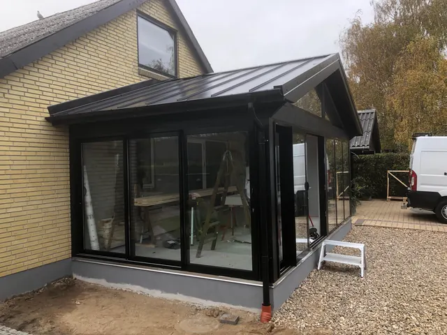 Tilbygning med glasparti og sort tag på muret villa — billede 11 af 23