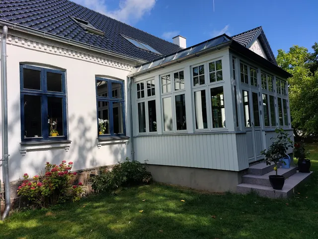 Havestuens lodrette træbeklædning op mod villaens vinduer — billede 3 af 23